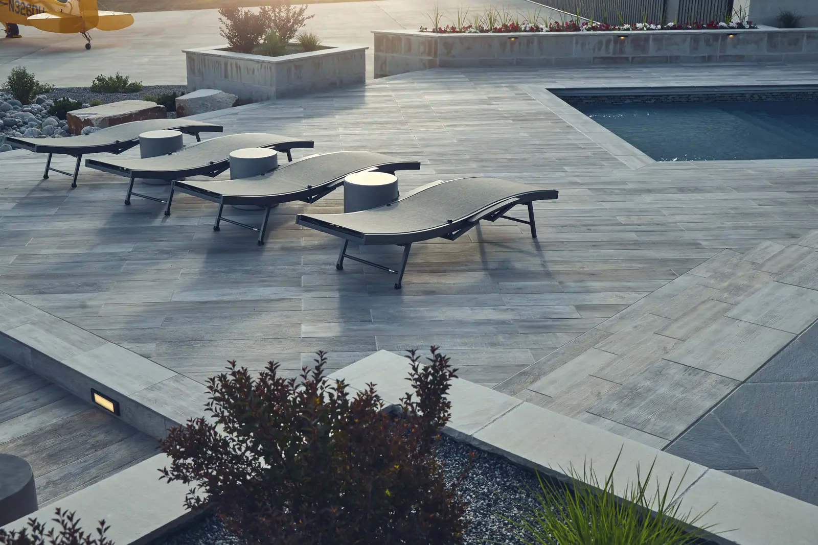 Chevron-laid porcelain pool deck with chaise lounges at the spa edge