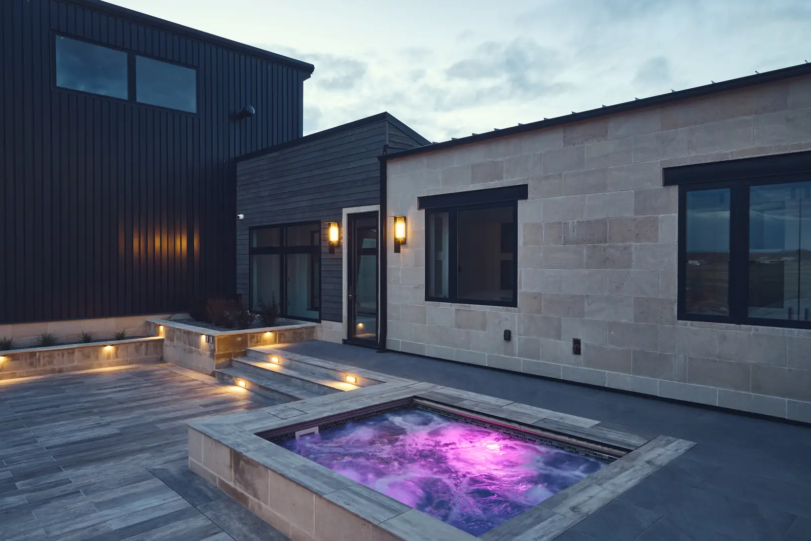 Purple-lit spa water beside limestone walls and accent lighting at night, Johnson Estate, Colorado